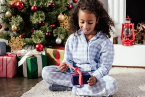 Little girl opening Christmas gift.