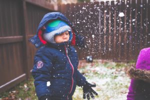 Christmas tradition: backyard camping. Little boy in winter coat, enjoying snow in the backyard.