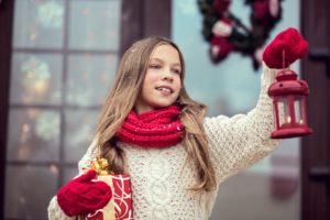 Little girl playing elf by bringing presents to the neighbors.