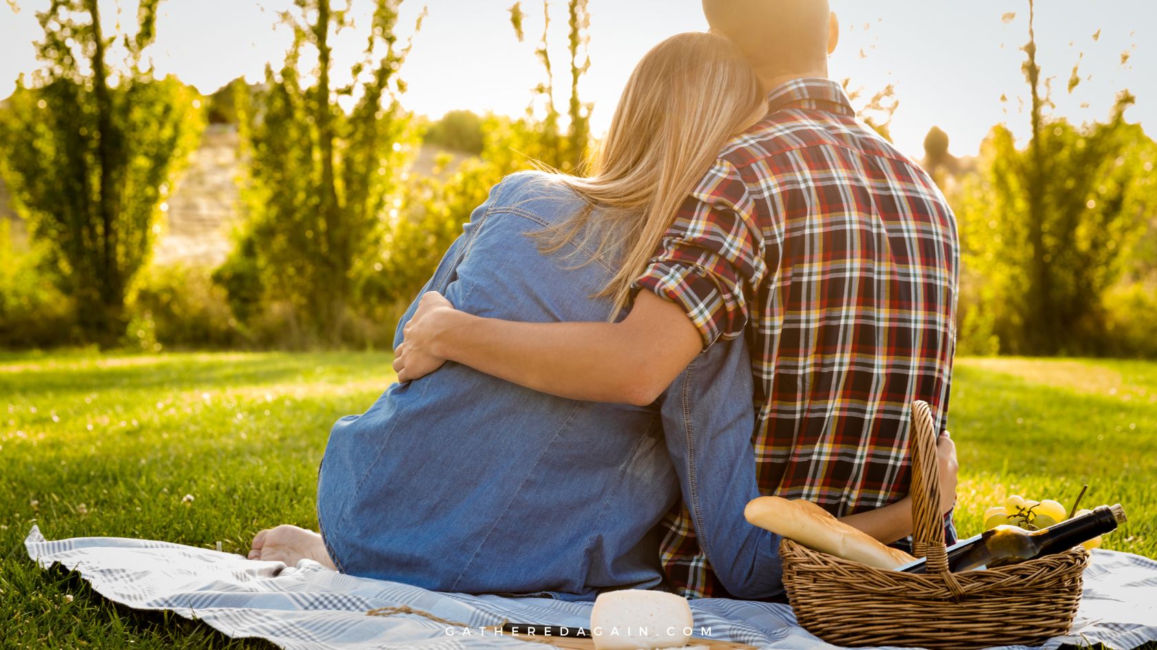 Couple hugging while enjoying a romantic picnic in the sunshine.